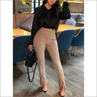 Stylish woman's casual outfit featured in K-AROLE store: black blouse, tan high-waisted pants, and chic leather handbag.