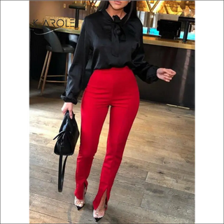 Stylish women's casual outfit: black long-sleeved blouse, high-waisted red pants, and open-toe heeled shoes, presented in a modern retail setting.
