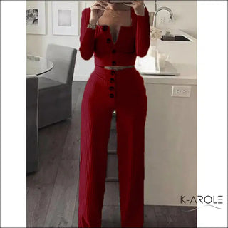Stylish red long sleeve jumpsuit with button details, shown in a modern interior setting at the K-AROLE store.