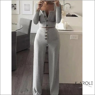 Elegant women's long-sleeve gray knit set with high-waisted pants and a buttoned top, displayed in a stylish home interior setting.